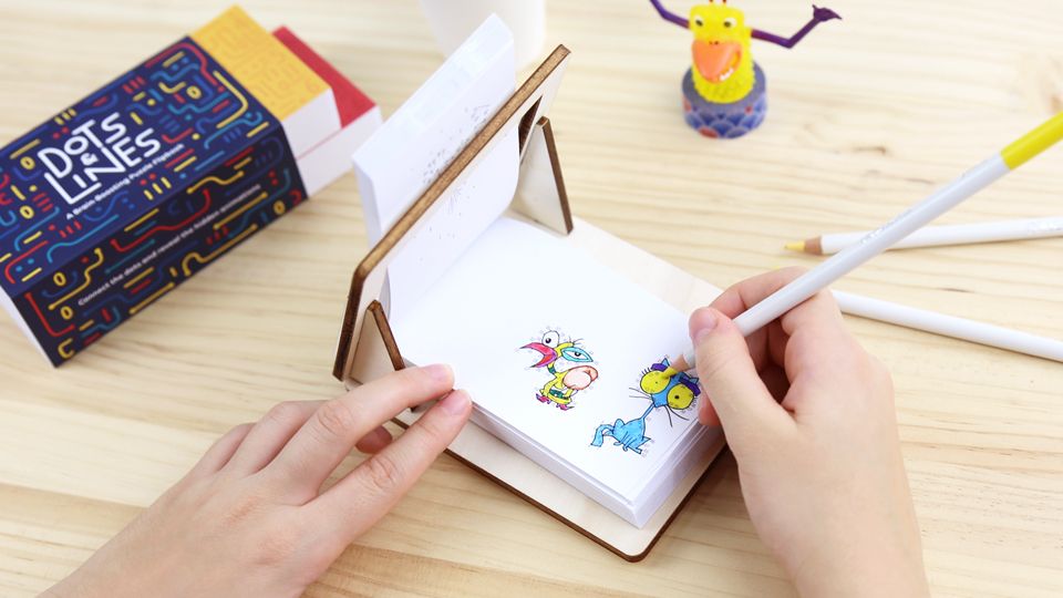 FLIPBOKU HOLDER - a practical tool that will enrich your experience with our interactive flip books Molecularis, Blanko and Dots &amp; Lines. It gives you some more freedom of movement while coloring, drawing, or connecting the dots.